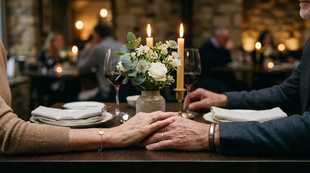 Table dressée pour un dîner d'anniversaire de mariage, mains d'un couple posées l'une sur l'autre Image