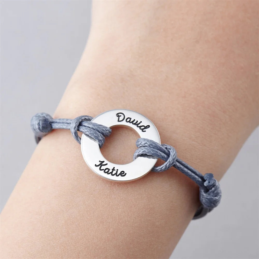 un poignet portant une bracelet en corde avec un anneau au milieu avec une gravure dessus c'est un bracelet personnalisé femme