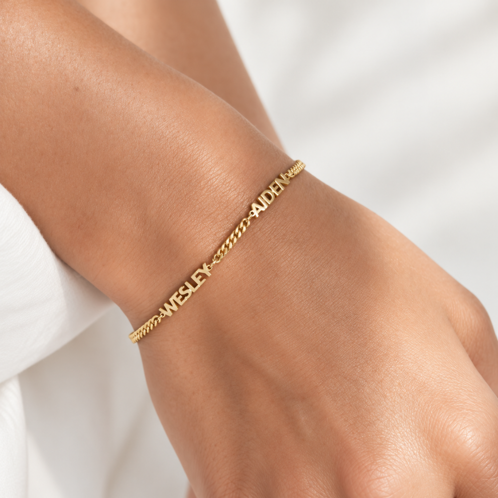 le poignet d'une femme portant un bracelet prénom or