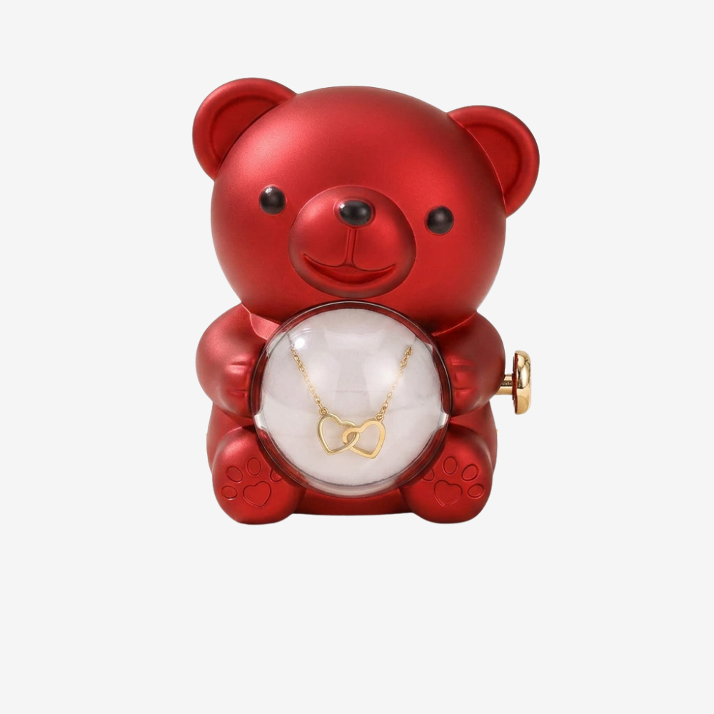 Vue de face de l'ourson rouge, pendentif cœurs entrelacés dorés visible à travers la sphère en verre