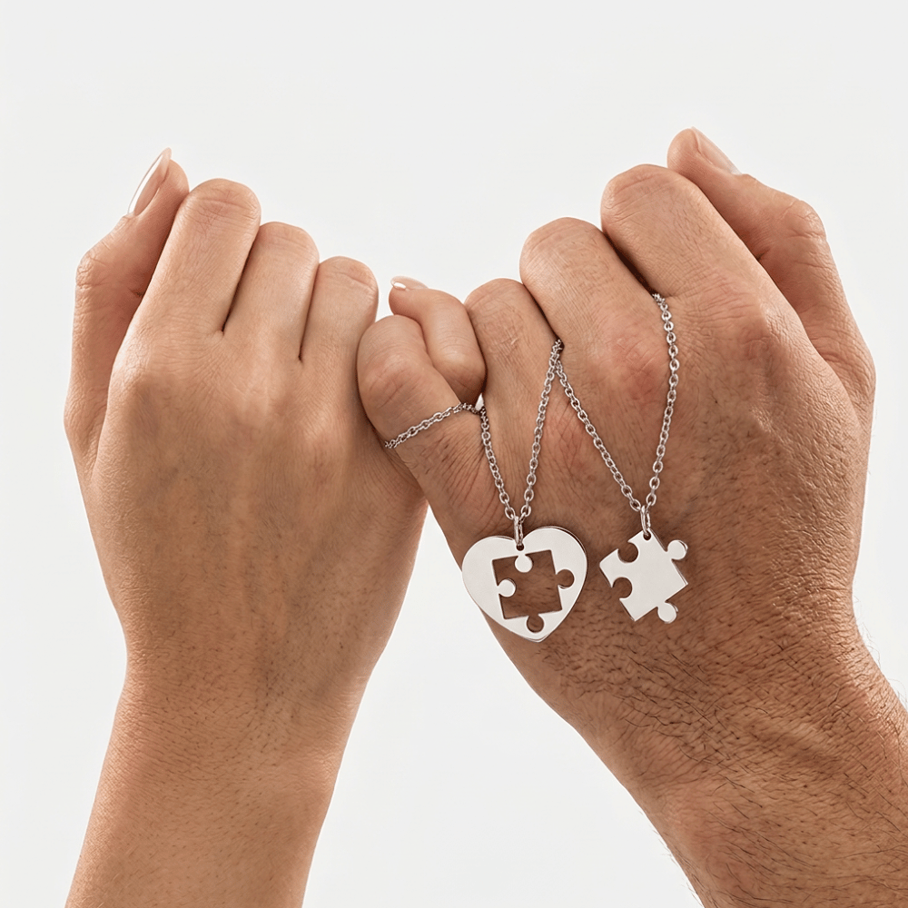Collier pour couple puzzle tenu par deux mains, pièces de puzzle argentées