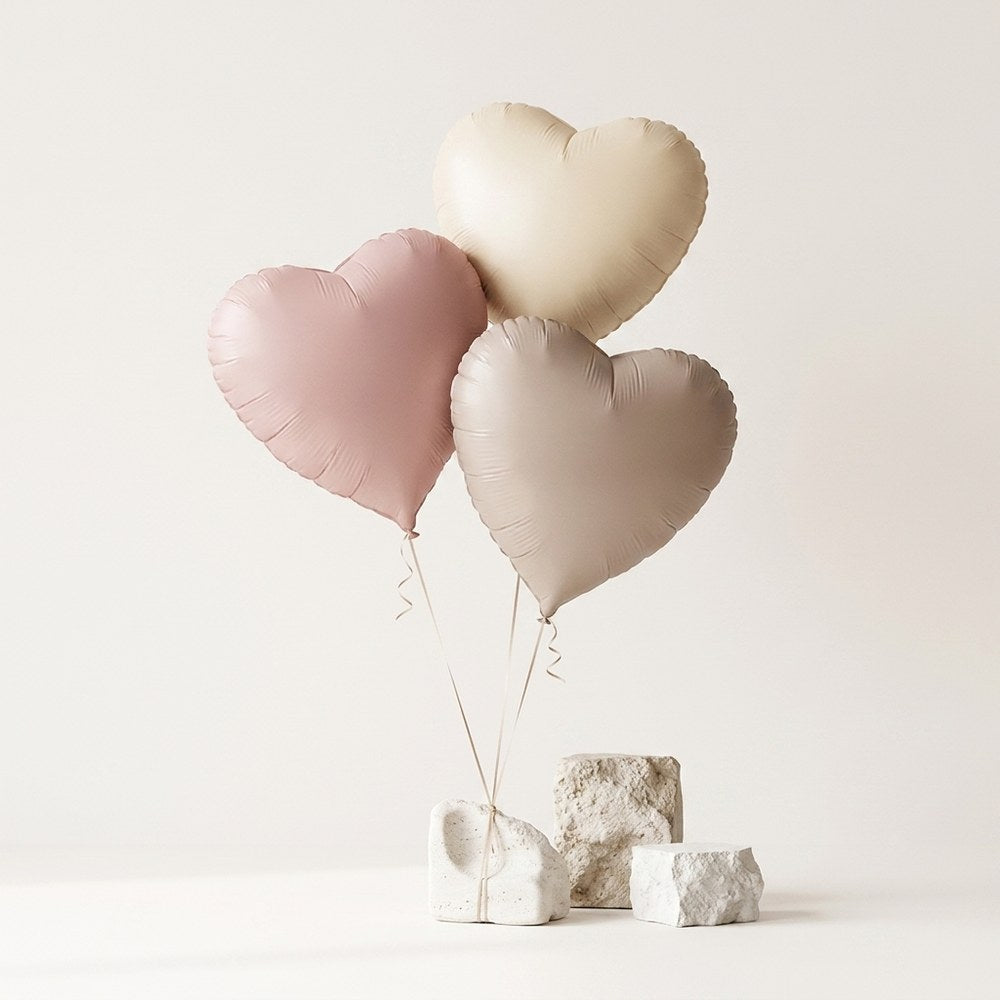 Ballons cœur pastel posés sur décor minéral ivoire