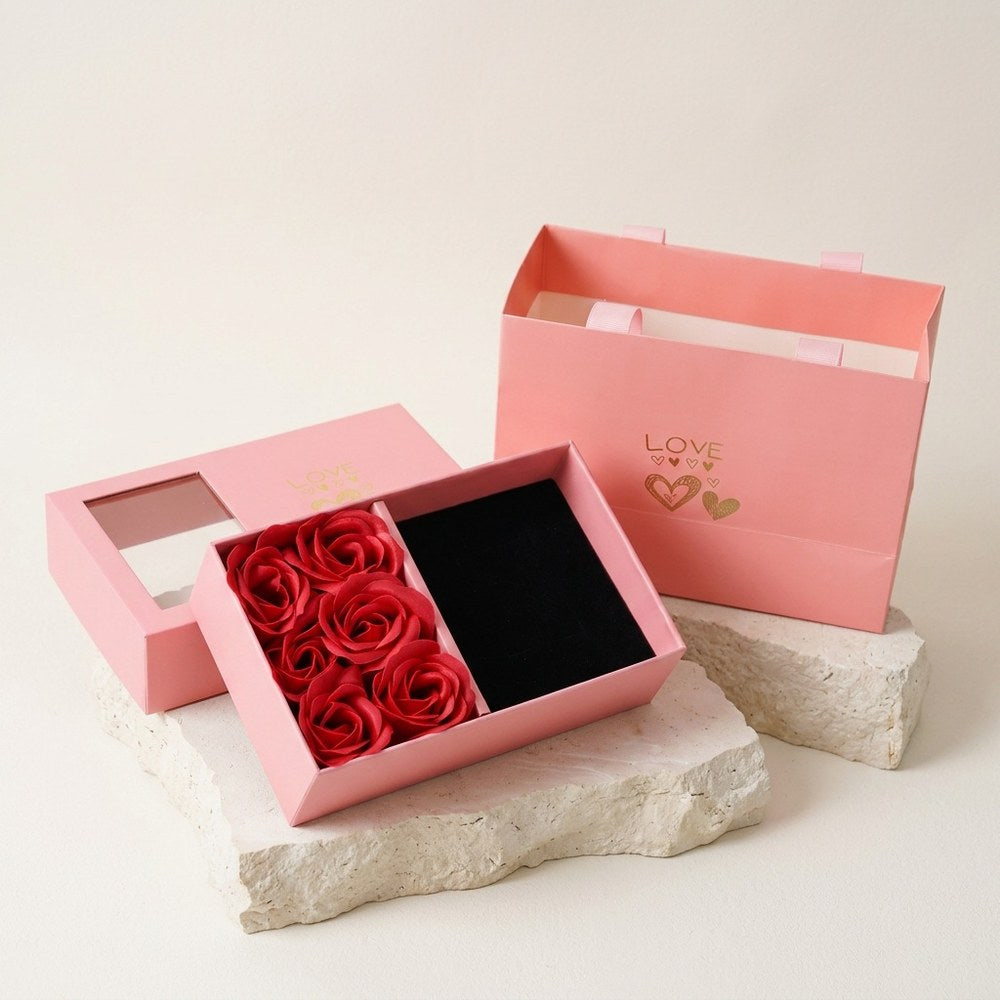 Boîte cadeau avec fenêtre sur roses éternelles posée sur décor minéral ivoire