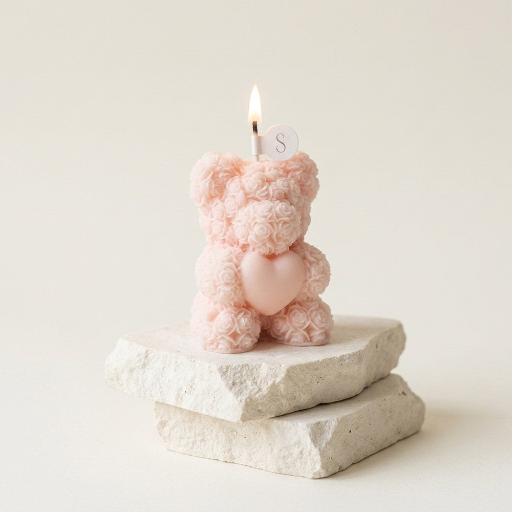 Bougie cadeau ourson fleuri posée sur décor minéral ivoire