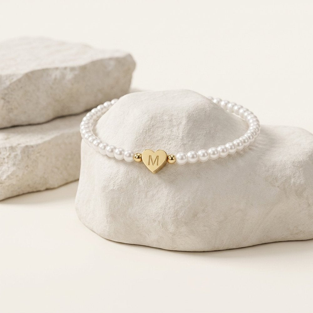 Bracelet cœur en perles blanches personnalisé, posé sur un support minéral ivoire