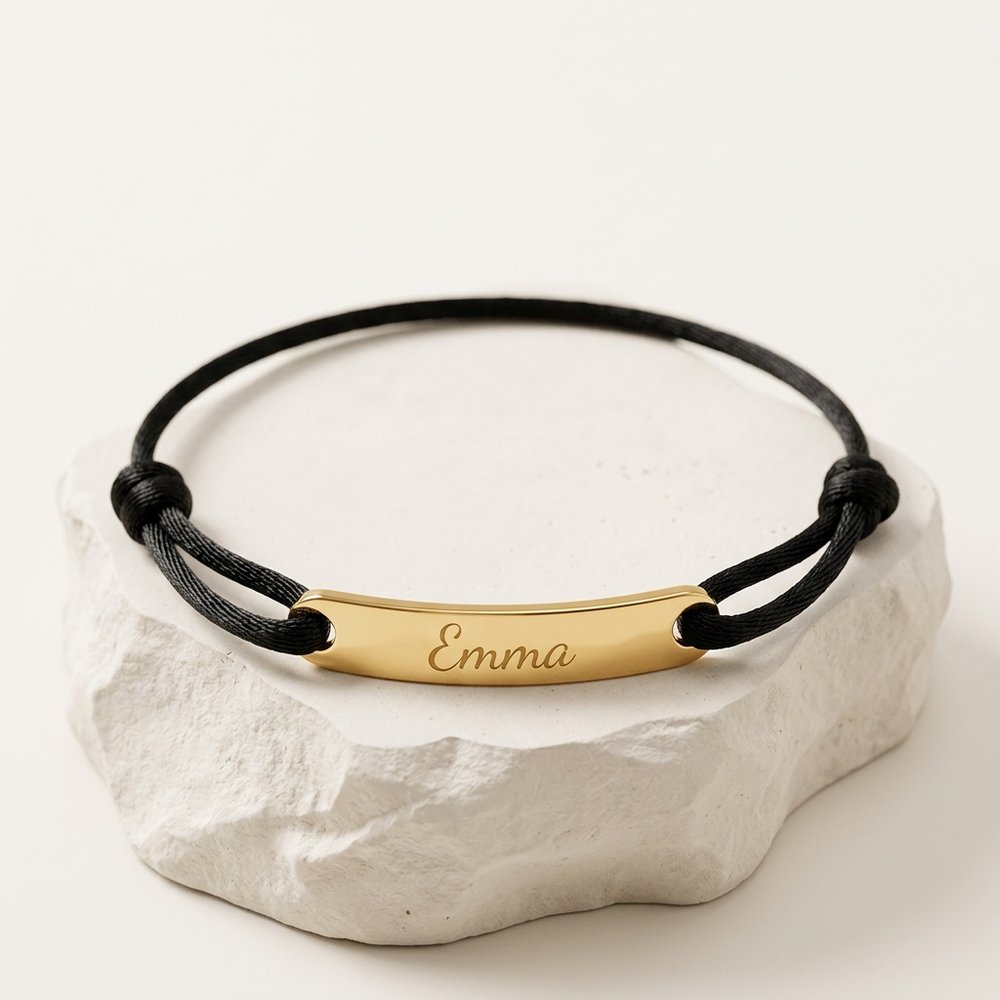 Bracelet corde personnalisable gravé du prénom Emma posé sur un support minéral ivoire