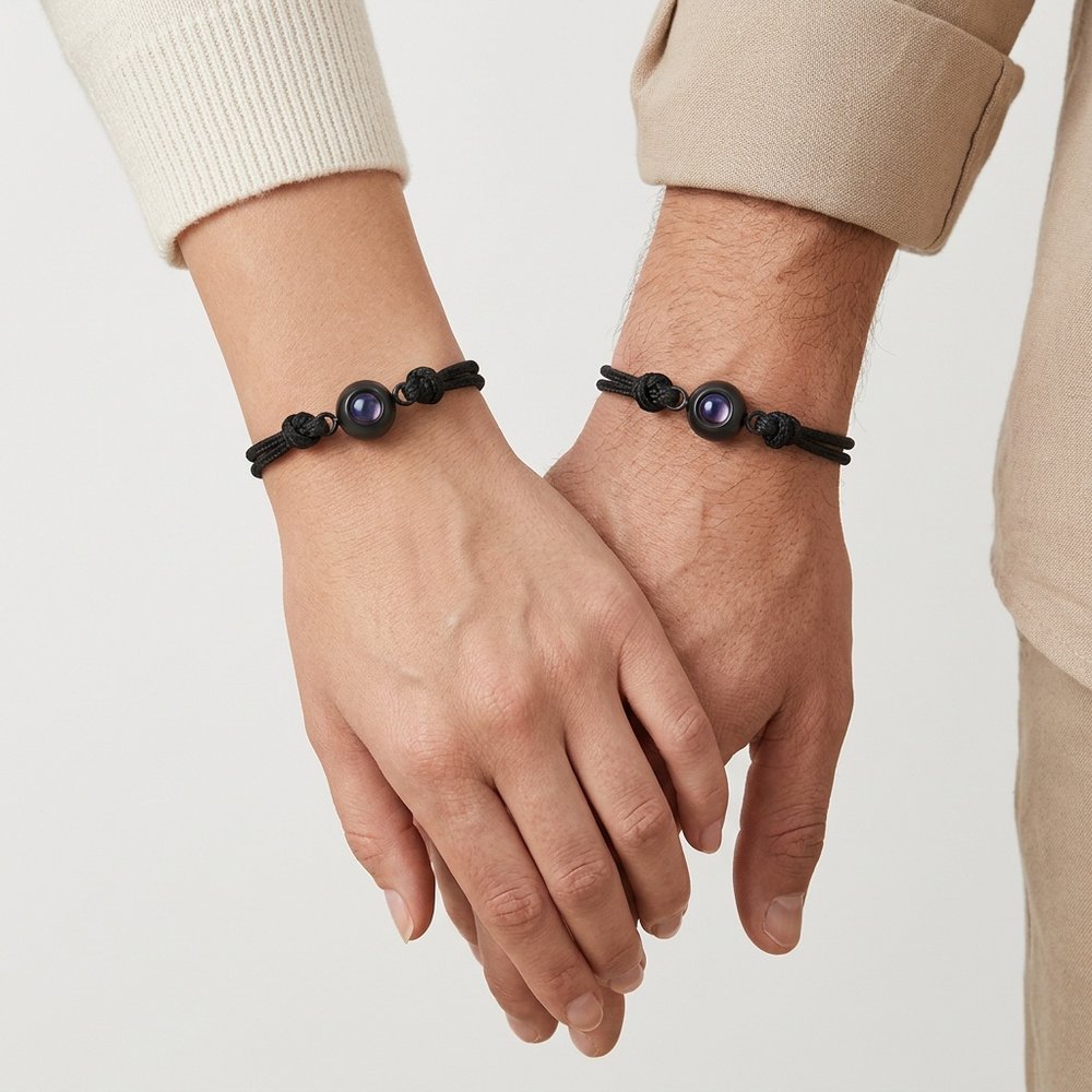 Bracelet couple avec photo projection porté par deux mains liées, un cordon noir à chaque poignet
