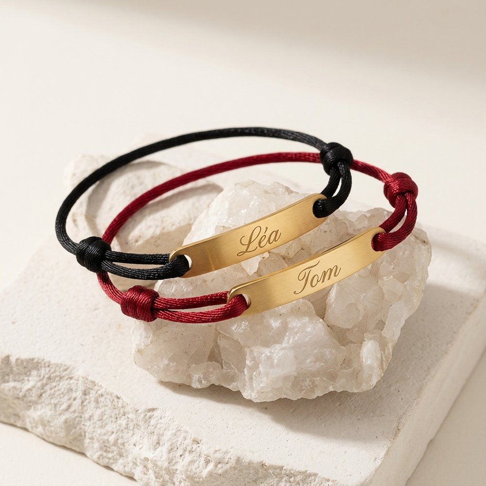 Deux bracelets cordon personnalisés à plaque gravée posés sur un support minéral ivoire