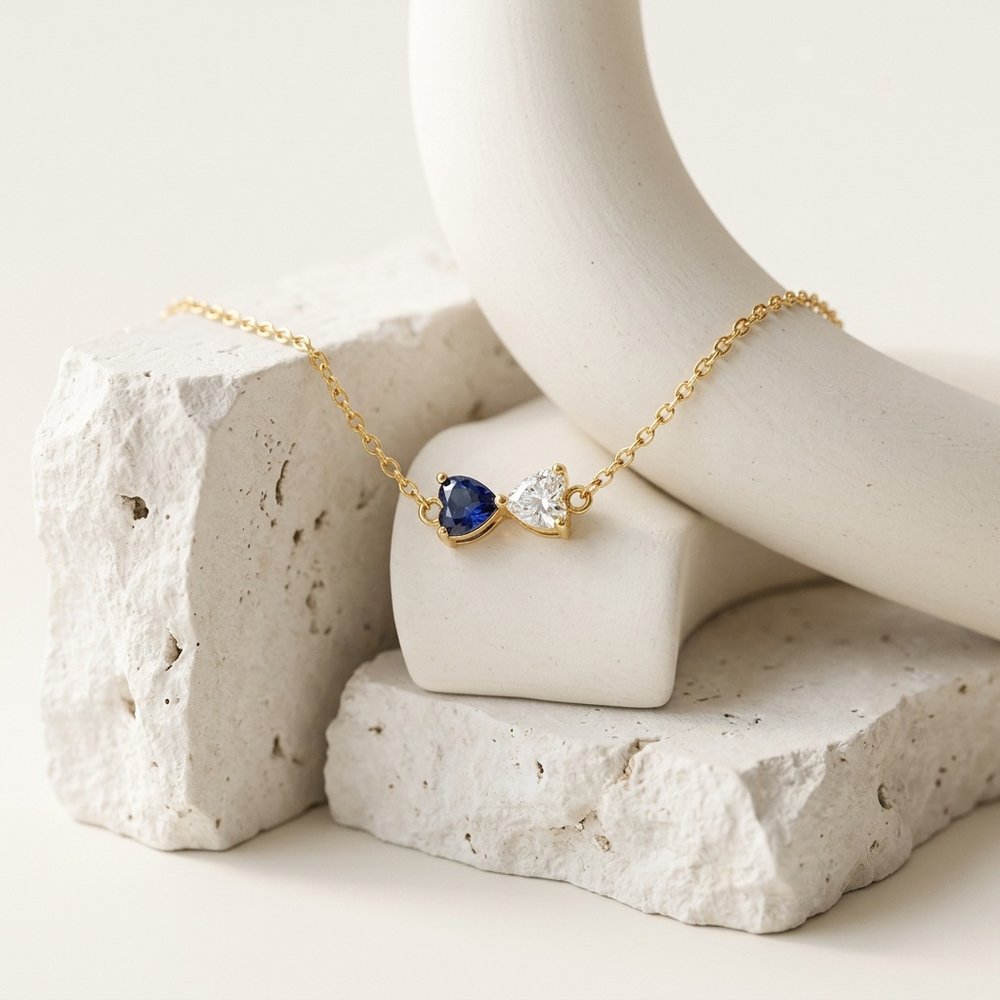 Bracelet de naissance duo de cœur posé sur un support minéral ivoire
