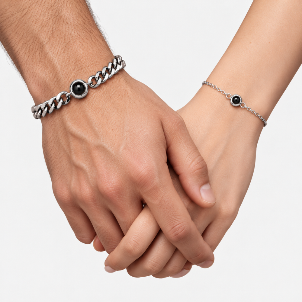 Bracelet homme et femme photo projection porté par un couple main dans la main, gourmette au poignet de l'homme et chaîne fine au poignet de la femme