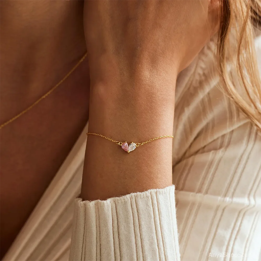 Bracelet Pierre de Naissance double en forme de cœur, présenté sur un poignet d'une femme blonde 