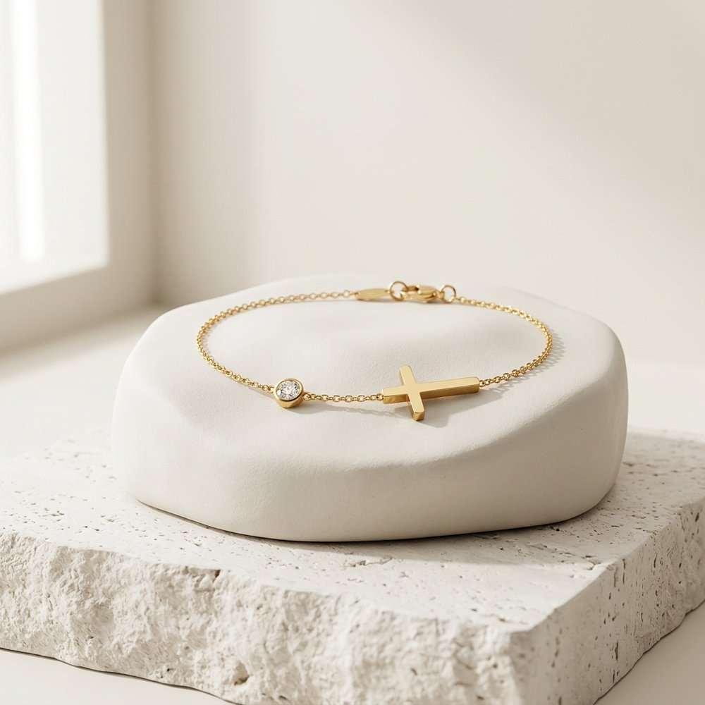 Bracelet pierre de naissance et croix posé sur un support minéral ivoire