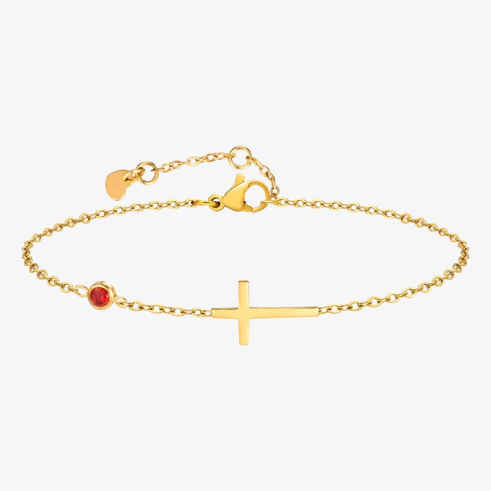 Bracelet avec une pierre de naissance rouge pour le mois de janvier. Bracelet a également une croix et c'est sur un fond neutre. 