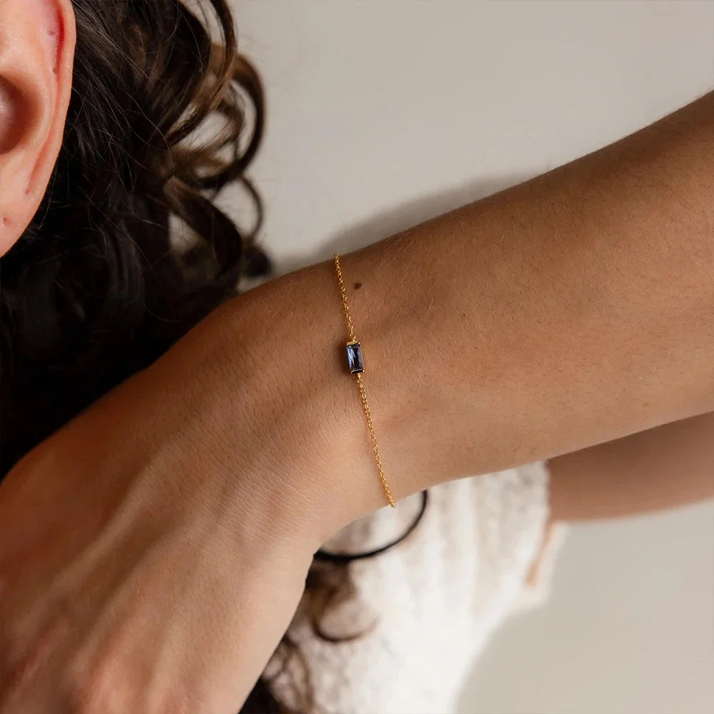 Une femme présente son poignet avec un bracelet Pierre de naissance minimaliste. 