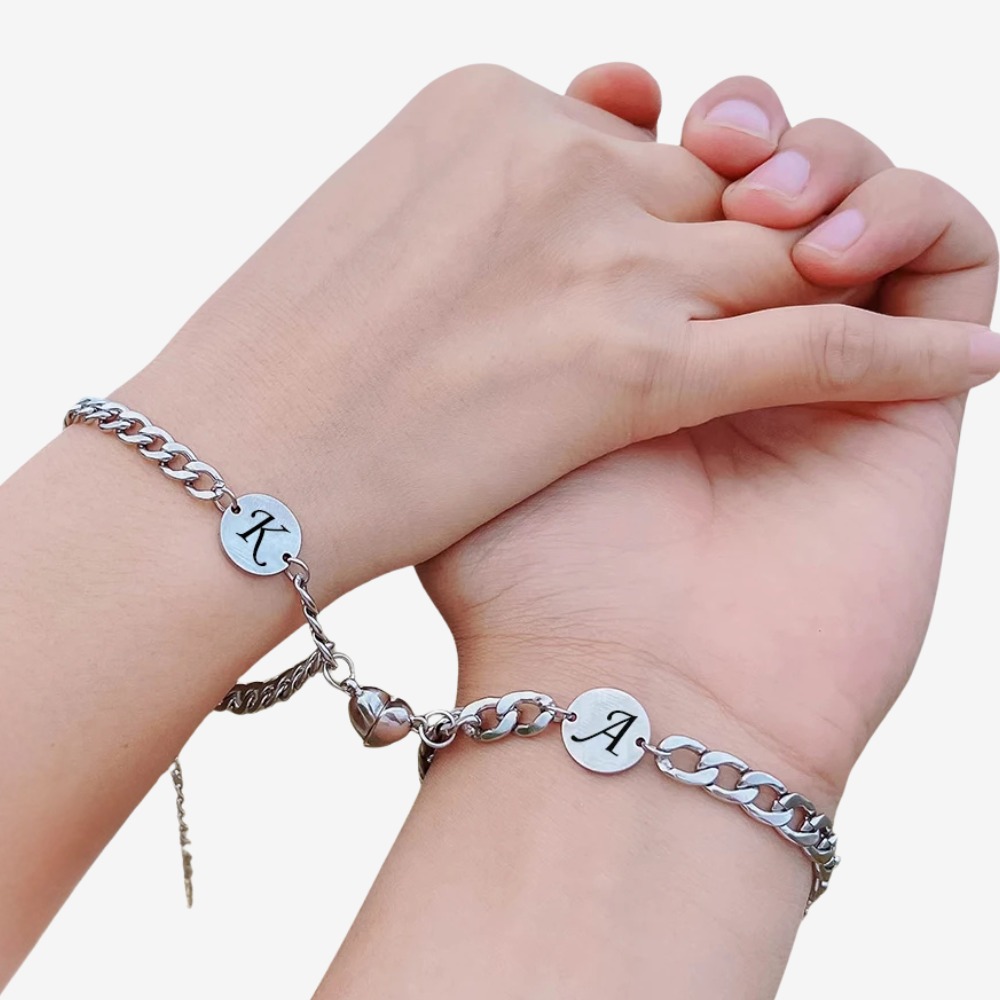 Bracelet connecté couple porté par deux poignets, aimant cœur reliant les initiales K et A