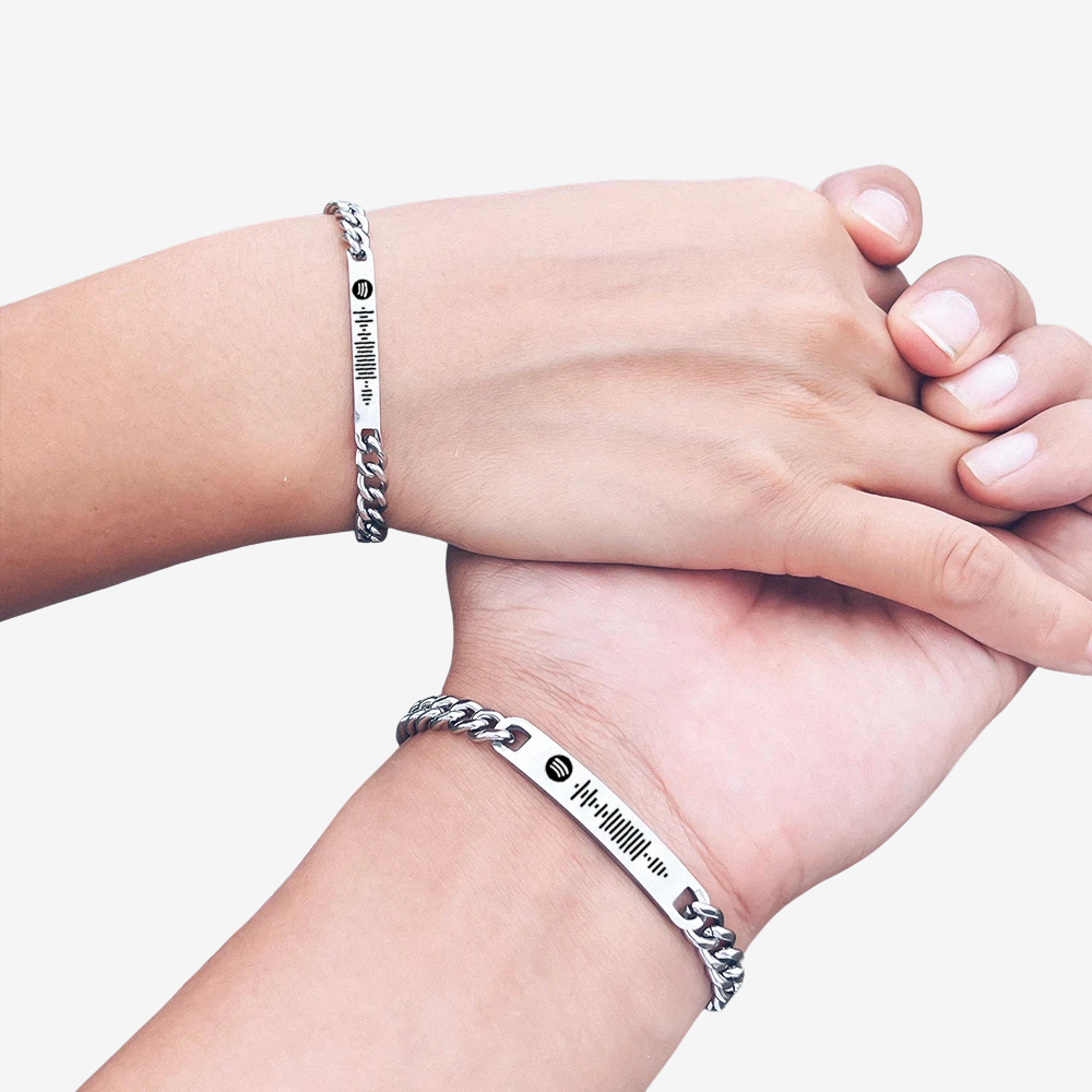 Bracelet couple en commun porté par deux poignets, gourmette argentée gravée d'un code Spotify