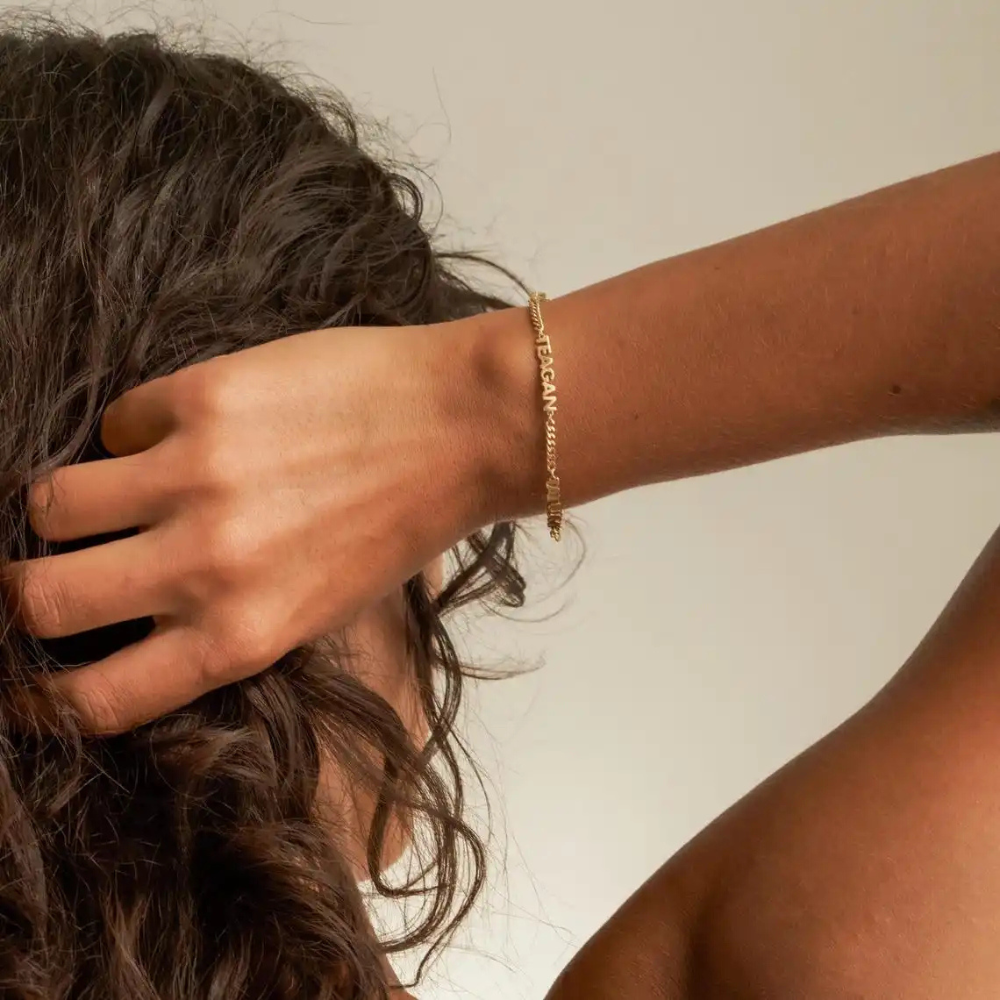 Bracelet prénom femme porté au poignet, chaîne dorée avec prénom gravé en lettres