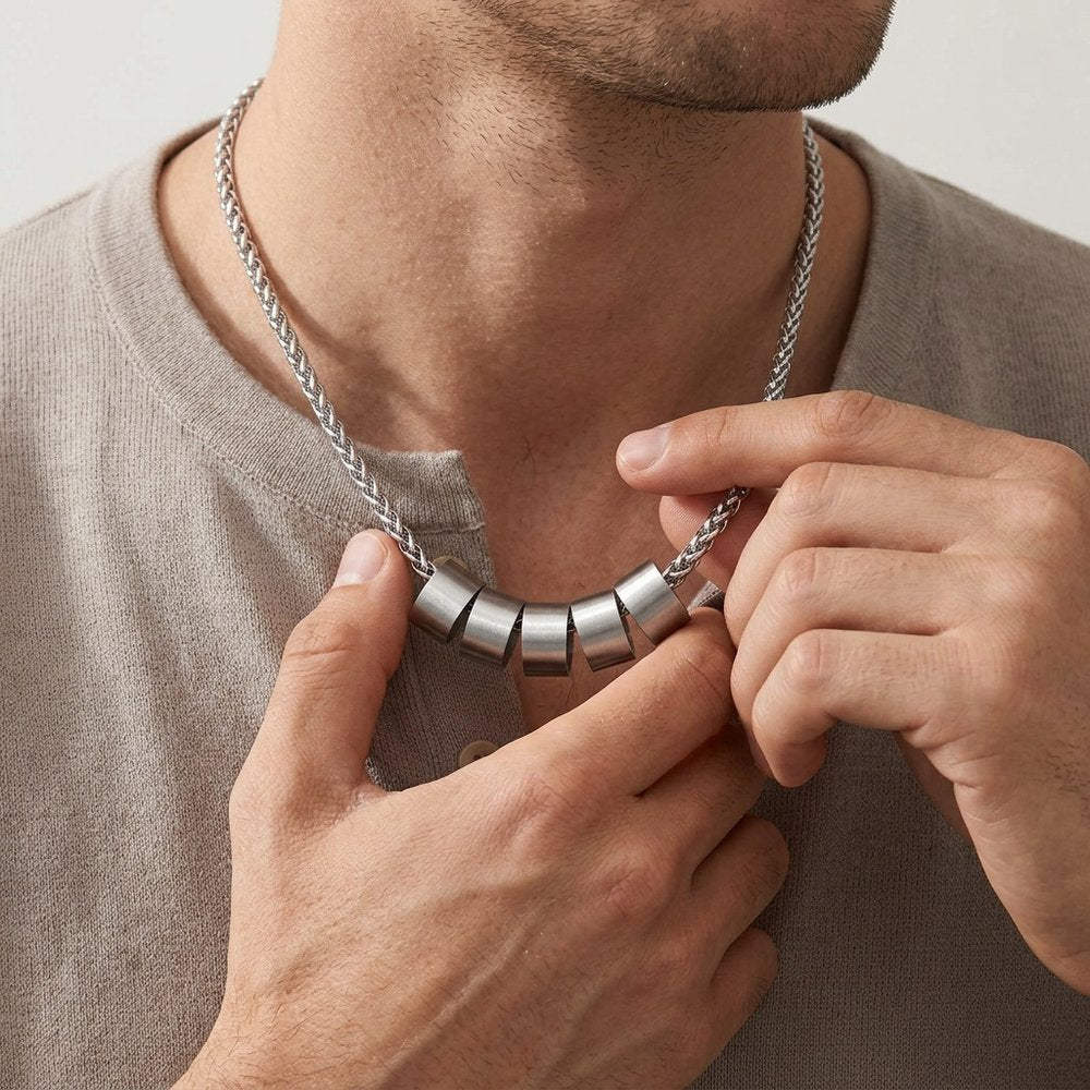 Homme ajustant son collier à perles gravées de prénoms