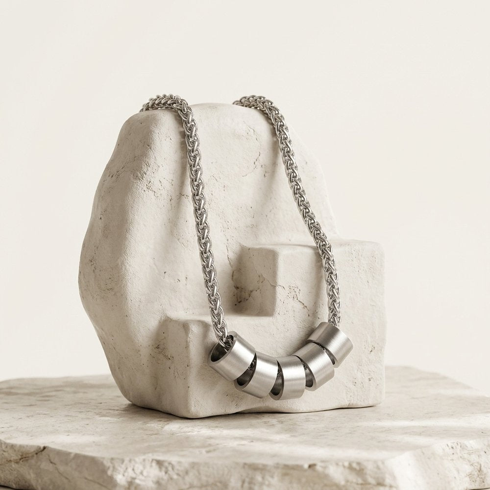 Collier homme personnalisé posé sur une pierre minérale ivoire