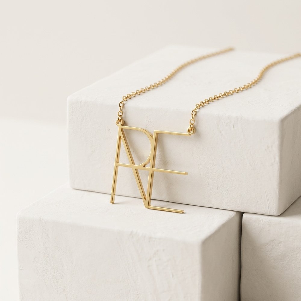 Collier monogramme posé sur une pierre minérale ivoire