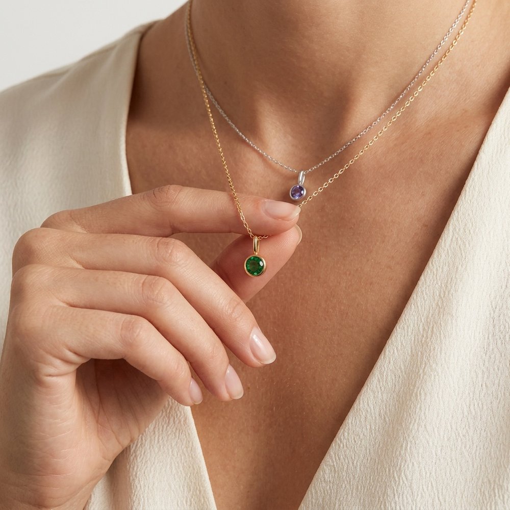 Collier pierre de naissance ronde, geste de main effleurant le pendentif
