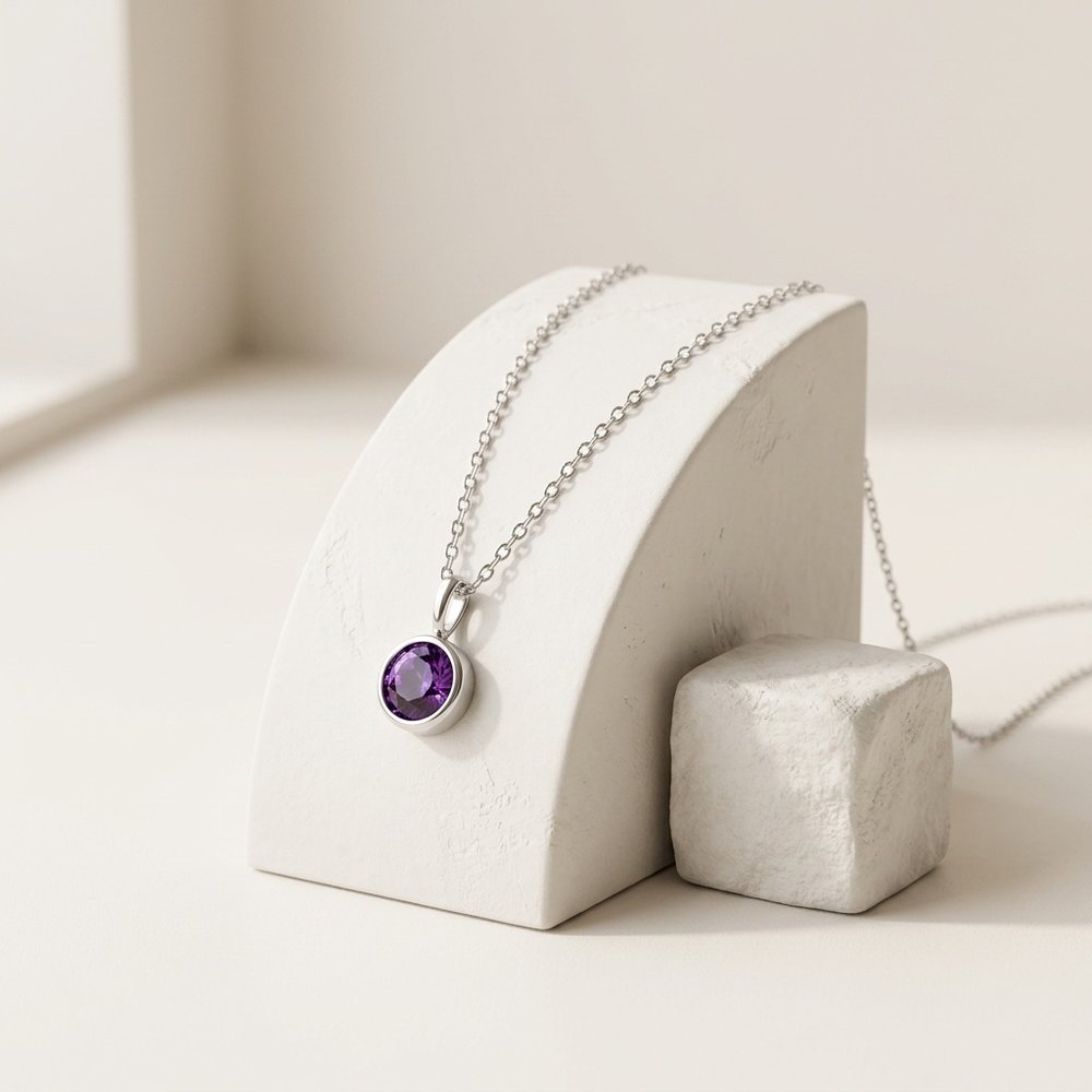 Collier pierre de naissance ronde posé sur un support minéral ivoire
