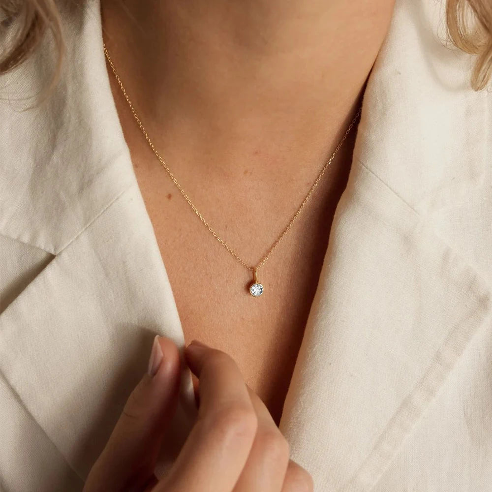 Collier pierre de naissance rond porté par une femme en tailleur