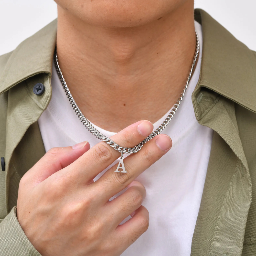Collier argent homme porté, main tenant le pendentif lettre initiale