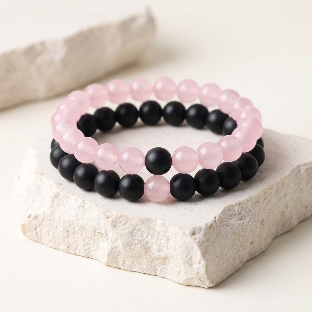 Deux bracelets perle couple rose et noir posés sur un support minéral ivoire